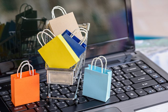 Five paper shopping bags and a shopping cart on a laptop keyboard. How to expand your product range with Pimberly