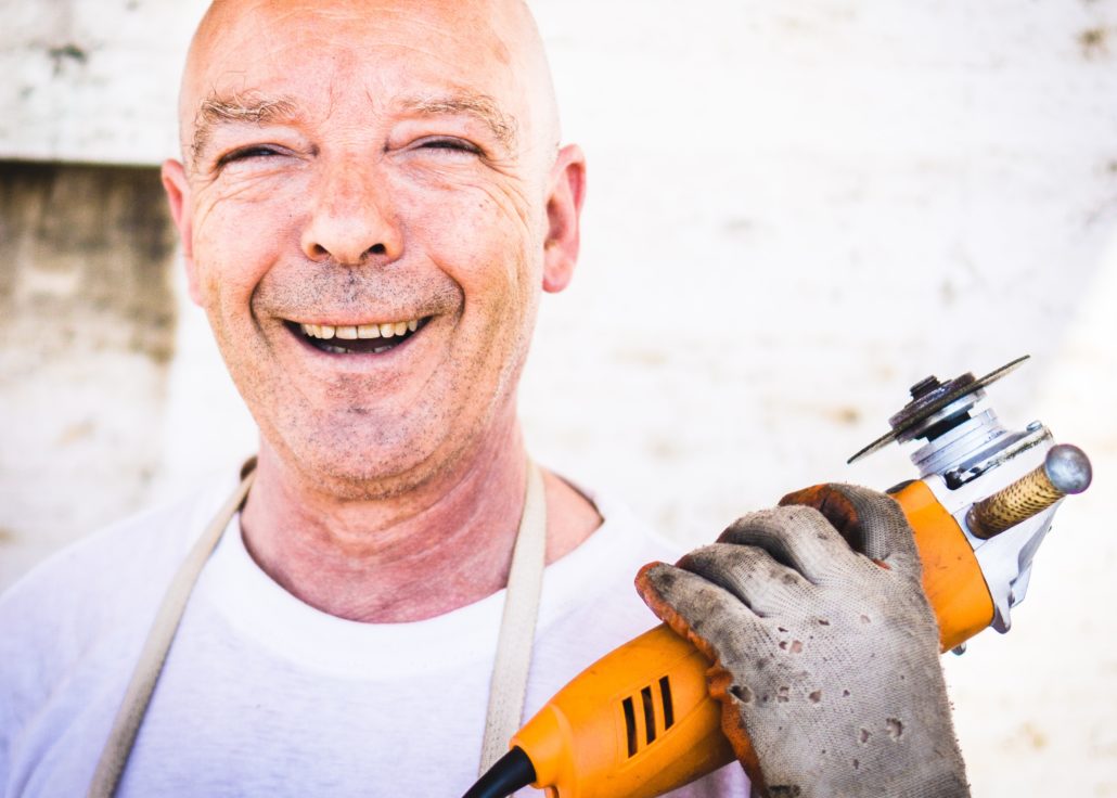 image of a man holding a drill, the man is smiling