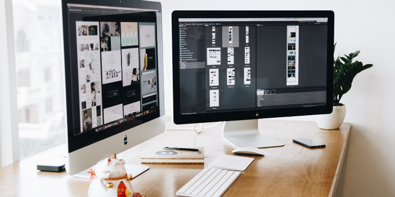 two apple mac screens side by side on a desk