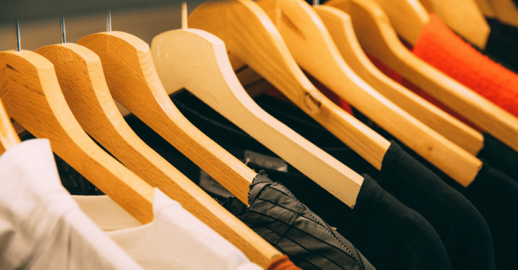 image of a rack of wooden coat hangers with different clothes on them