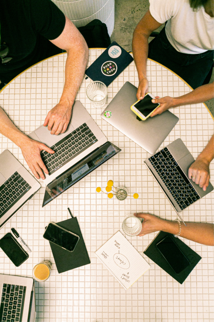 image of workers around a table with their computers and mobiles on the table