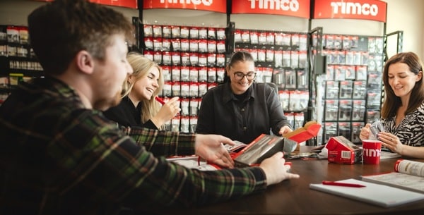 Group collaborating around a table with TIMCO hardware products and displays in the background